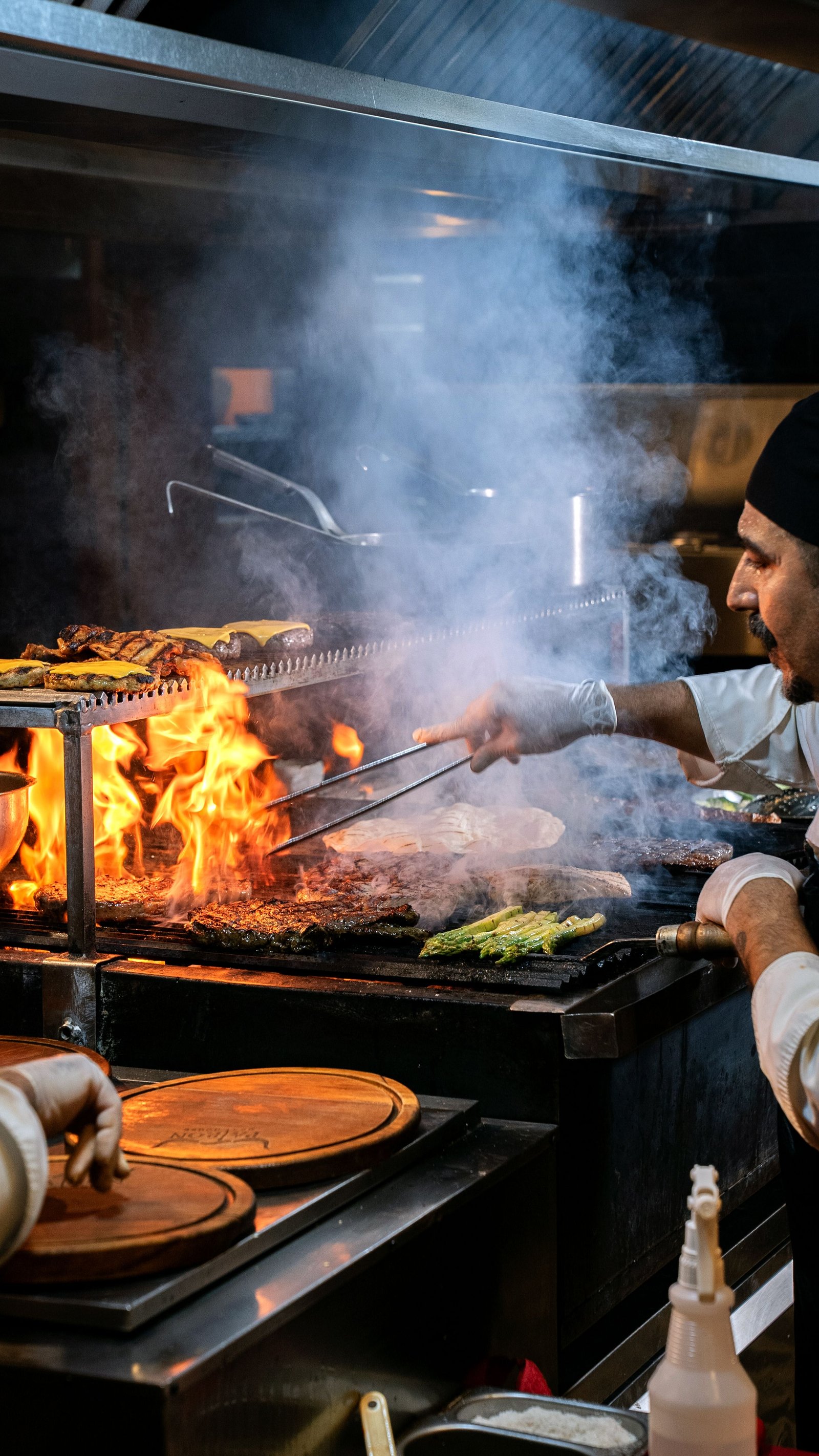 Chef grilling over live flame in a professional open kitchen